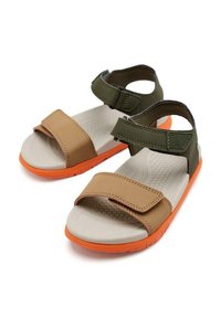 Sandales marron et vert avec des sangles réglables, semelle texturée beige et semelle en caoutchouc orange avec des motifs de traction.