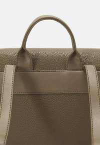 Měkká olivově zelená kožená kabelka s výraznou horní rukojetí a plochými popruhy. Má strukturované tělo a hladké detaily.