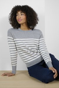 Pull gris rayé avec des rayures horizontales gris clair et blanches, col rond et poignets côtelés, associé à un jean foncé sur une surface en bois.
