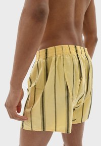 Gula randiga boxershorts i mjukt tyg, med tunna svarta vertikala linjer, resårmidja och lös passform.