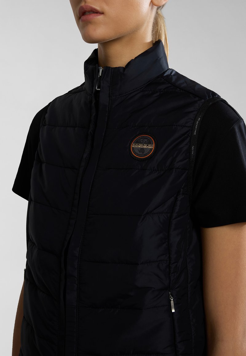 Czarna kamizelka puchowa z wysokim kołnierzem, pikowanym wzorem i zapinanymi na zamek kieszeniami. Ma okrągłą naszywkę z logo na klatce piersiowej. Gładka satynowa faktura.