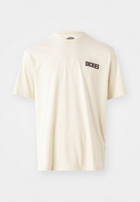 Lys beige bomulds t-shirt med korte ærmer og rund halsudskæring. Har en mørkebrun logo tekst "DICKIES" på venstre brystområde.