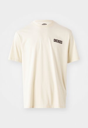 T-shirt en coton beige clair avec des manches courtes et un col rond. Présente un logo textuel brun foncé "DICKIES" sur la partie gauche de la poitrine.