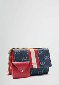 Džínová crossbody taška s červenými koženými detaily, zlatým řetízkem a logem. Součástí je malý odpovídající obal na karty.