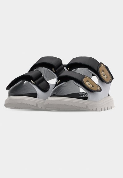 Παιδικά γκρι και μαύρα σανδάλια με δύο ρυθμιζόμενους ιμάντες και διακοσμητικά με πρόσωπο χαμογελαστού αρκούδου στους πάνω ιμάντες.