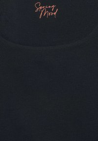 Mörkblå ribbad linne med rundad halsringning och texten "Vårkänsla" i korallfärgad kursiv högst upp i mitten.