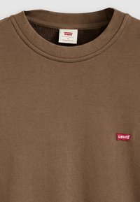 Bruin katoenen crewneck t-shirt met een rood Levi's logo patch op de linkerborst. Standaard pasvorm met geribbelde halslijn en gestructureerde stof.