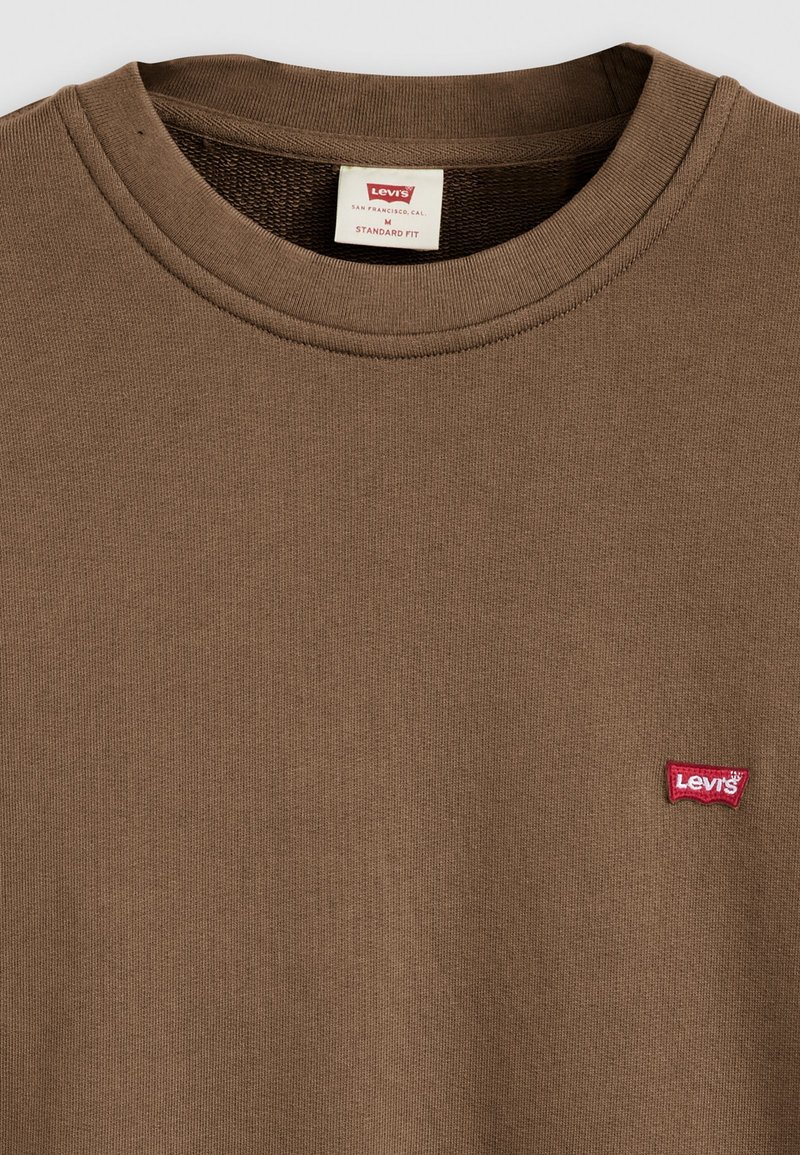 Braunes Baumwoll-Crewneck-T-Shirt mit einem roten Levi's-Logopatch auf der linken Brust. Normale Passform mit geripptem Rundhalsausschnitt und strukturiertem Stoff.