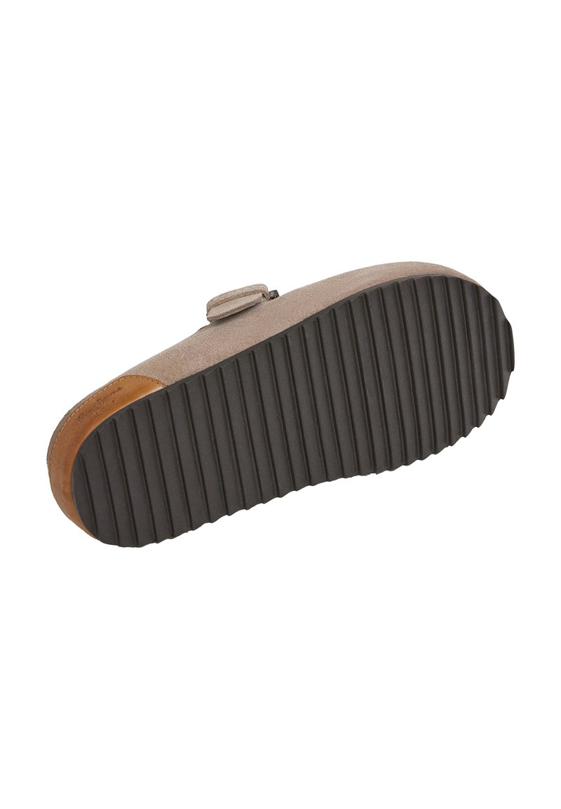 Chaussure avec un dessus en daim marron clair, dotée d'une sangle et d'une semelle en caoutchouc noire texturée avec des cannelures. Accents dans un marron plus foncé.