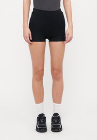 Black athletic shorts with an elastic waistband, featuring a fitted design that extends to mid-thigh. Paired with black sneakers and white socks.
