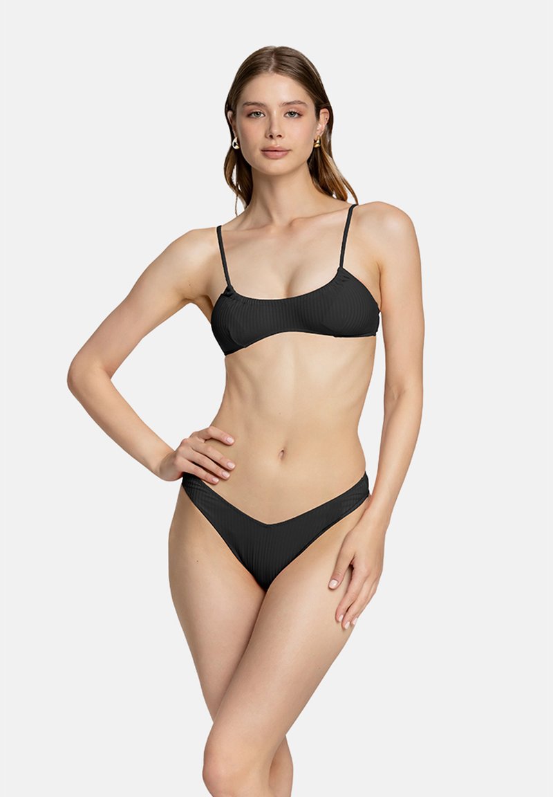 Bikini nero a costine con spalline sottili e regolabili. Il top presenta una scollatura a forma di barca, mentre il fondo ha un taglio a vita bassa con copertura minima.