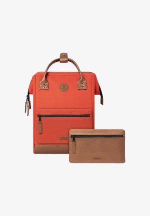 Sac à dos orange avec une finition texturée, des accents marron, une poignée supérieure et une poche zippée à l'avant. Comprend une pochette zippée marron assortie.