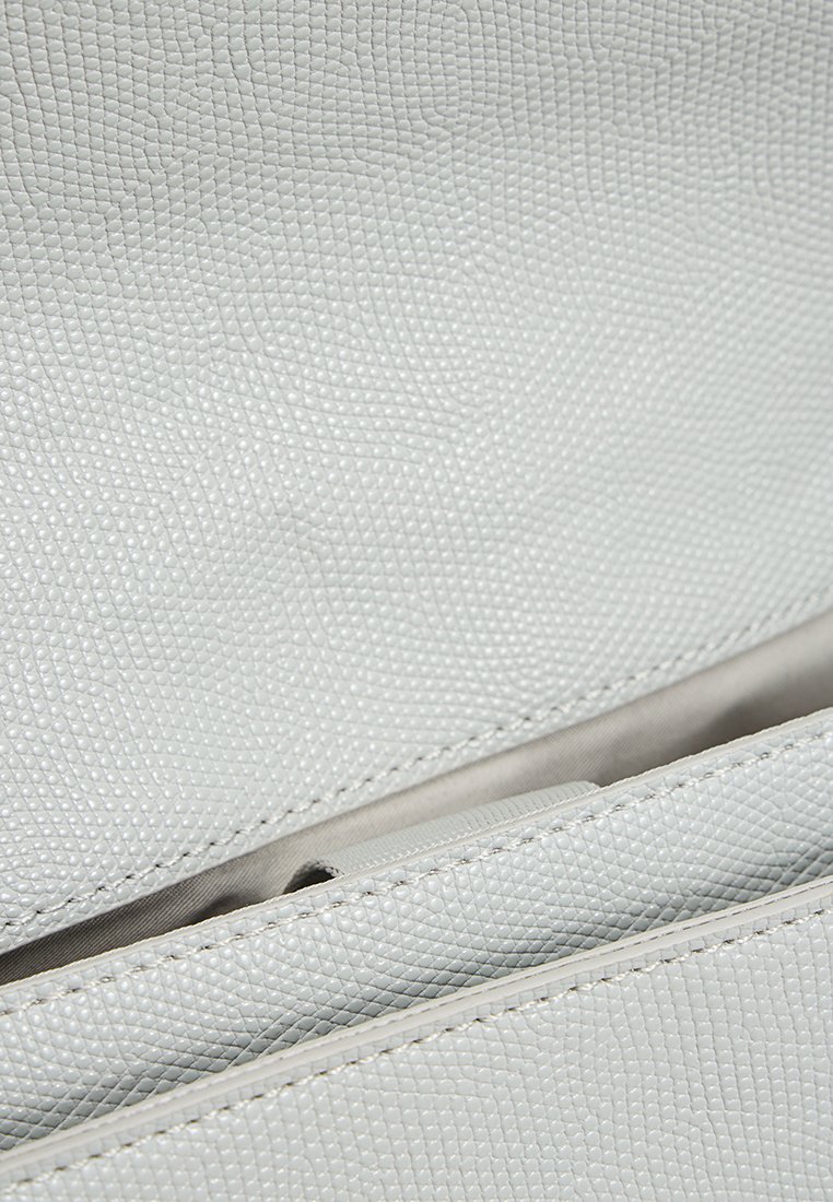 Intérieur de sac en cuir texturé gris clair avec une poche zippée et un revêtement lisse, caractérisé par des coutures précises et un design structuré.