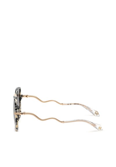 Lunettes de soleil rondes écaille de tortue vues de côté avec des branches en métal doré ondulé et des embouts de branches en plastique transparent.