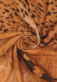 Tessuto in stampa leopardata nelle sfumature di marrone e arancione, caratterizzato da una texture liscia con motivi maculati scuri e una caduta morbida e fluida.