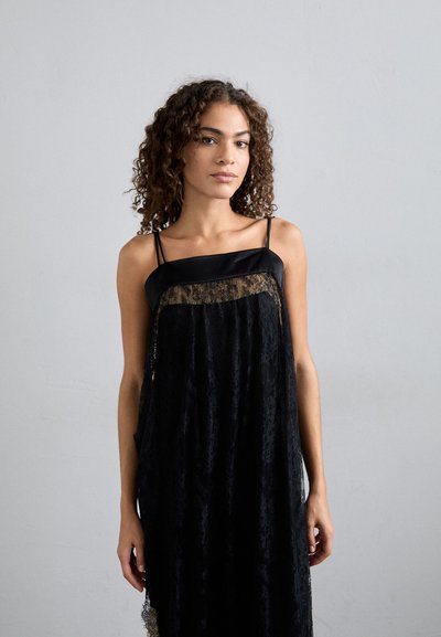 Μαύρο φόρεμα από δαντέλα με μετάξι, διαφανή μπροστινή πάνελ από δαντέλα και ροή σιλουέτας. Υφή υφάσματος με περίπλοκα σχέδια.