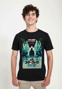 Svart bomullströja med ett grafiskt tryck som visar en Star Wars-scen med Darth Vader och rymdskepp. Texten innehåller japanska tecken och "40周年."