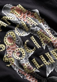 Czarny sweatshirt z ilustracją koi w odcieniach szaro-pomarańczowych. Złote ćwieki tworzą napis "SOCIAL CLUB" w widocznym miejscu.