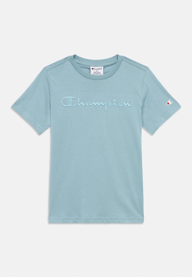 Λευκό μπλουζάκι κοντό μανίκι σε ανοιχτό μπλε χρώμα με κεντημένο το λογότυπο "Champion" στο στήθος και μικρό έμβλημα Champion στο αριστερό μανίκι.