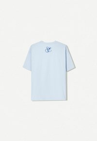 T-shirt en coton bleu clair avec un col rond et des manches courtes. L'arrière présente un graphique bleu avec un "S &" en cursive et un cœur.