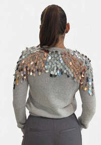 Maglione grigio con grandi paillettes circolari lucide sulle spalle, che offrono un accento testurizzato. La vestibilità è casual e su misura.