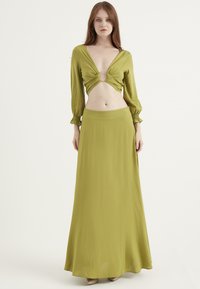 Olivgrön tvådelad outfit bestående av en djup V-ringad crop top med knutdetalj och en höglivad maxikjol i lätt tyg.