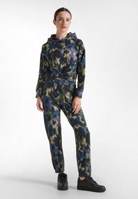 Hooded trainingspak in zwart, groen, blauw en paars met een patroon. Het sweatshirt heeft een gedraaid voorpaneel; de broek heeft elastische boorden en zakken.