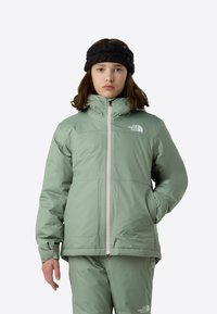 Ανοιχτό πράσινο, μονωμένο μπουφάν με ψηλό γιακά και μπροστινό φερμουάρ που φέρει λευκό λογότυπο. Λεία υφή, μακριά μανίκια και πλαϊνές τσέπες.