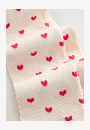 Kniehohe Socken in Hellrosa mit roten Herzmustern. Der Stoff hat eine gerippte Textur, die das wiederkehrende Herzdesign hervorhebt.