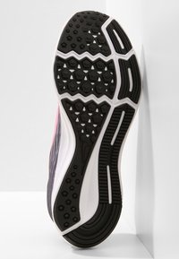 Sole di sneaker in bianco e nero con un motivo testurizzato, caratterizzato da forme esagonali e romboidali per presa e trazione. Accenti in rosa e grigio.