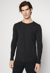 Schwarzes Langarm-T-Shirt aus weichem Material mit runder Halsausschnitt und taillierten Ärmeln, das ein einfaches Design ohne Muster aufweist.