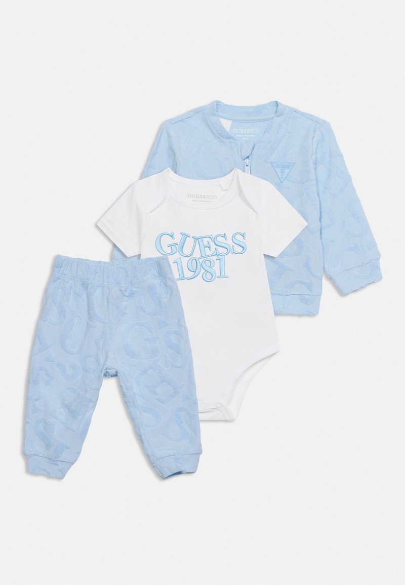 Completo di abbigliamento per neonati con giacca azzurro chiaro a fantasia e pantaloni, e body bianco a maniche corte con scritta blu "GUESS 1981".