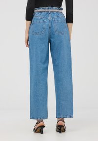 Jasnoniebieskie dżinsy z wysokim stanem, o luźnym kroju, z elastycznym paskiem w talii oraz dwoma kieszeniami z tyłu. Posiadają surowe wykończenie i teksturowany materiał.