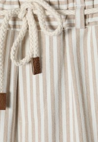 Pantalones cortos de algodón con cordón, que presentan rayas verticales en blanco y marrón claro, un cordón trenzado de color crema y detalles de cuero marrón.