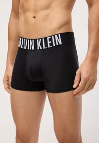 Crne bokserice s širokim elastičnim pojasom s brendom "CALVIN KLEIN". Glatka tkanina i uski dizajn poboljšavaju udobnost.