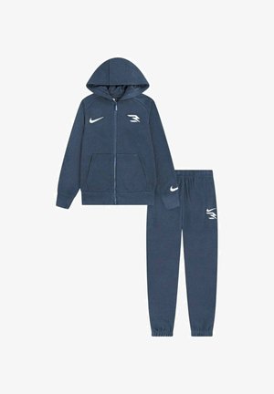 Felpa con cappuccio blu navy con zip e pantaloni della tuta abbinati con loghi Nike bianchi e una "R" stilizzata sul petto, sulla manica e sulla gamba dei pantaloni.