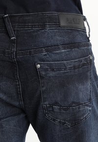 Mörkblå denimjeans med en texturerad yta, utrustade med en läderlapp märkt "BLEND", ton-i-ton-sömmar och två bakfickor med detaljer.