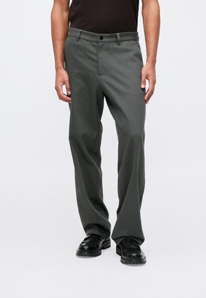 Grå skräddarsydda byxor med rak ben design, med framfickor, bälteshällor och knappstängning. Bärs med svarta skor.