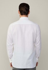 Witte, lange mouwen blouse met een recht gesneden ontwerp, subtiele textuur, een button-down kraag en knoopmanchetten. De achterkant toont een gladde afwerking.