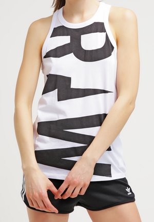 Top sin mangas blanco con letras negras audaces que dicen "RAW". Combinado con pantalones cortos deportivos negros con un logo de la marca en blanco. Textura de tela suave.