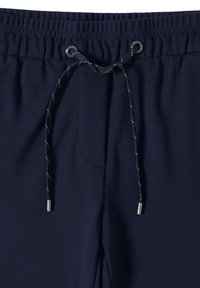 Marina joggingbyxor med elastisk midja, justerbar dragsko och metallagletter. Har en mjuk yta och sidfickor.