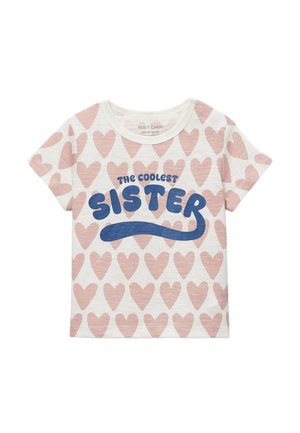 T-shirt blanc à manches courtes pour enfants avec un motif de cœurs roses et un texte bleu sur le devant indiquant "La sœur la plus cool".
