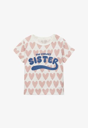 T-shirt blanc à manches courtes pour enfants avec un motif de cœurs roses et un texte bleu sur le devant indiquant "La sœur la plus cool".
