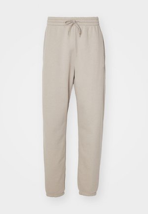 Beige sweatpants made of soft fabric, featuring an elastic waistband with drawstring, side pockets, and tapered legs.