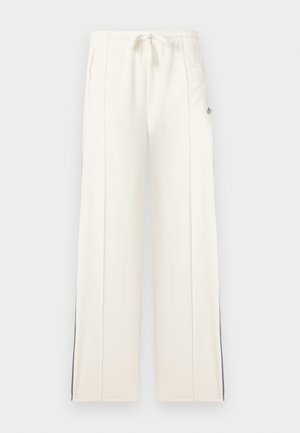 Witte sweatpants met wijde pijpen, een elastische taille met trekkoord, zijzakken, verticale naaddetails en subtiele zwarte strepen langs de buitenkant van de broekspijpen.
