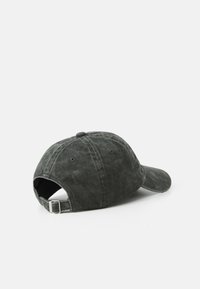 Casquette de baseball en coton gris foncé avec une visière courbée, une sangle métallique réglable et une texture douce. Présente des accents cousus et des trous de ventilation.