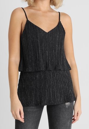 Haut sans manches noir en V avec des fines bretelles et des rayures métalliques verticales discrètes, porté avec un jean gris foncé déchiré.