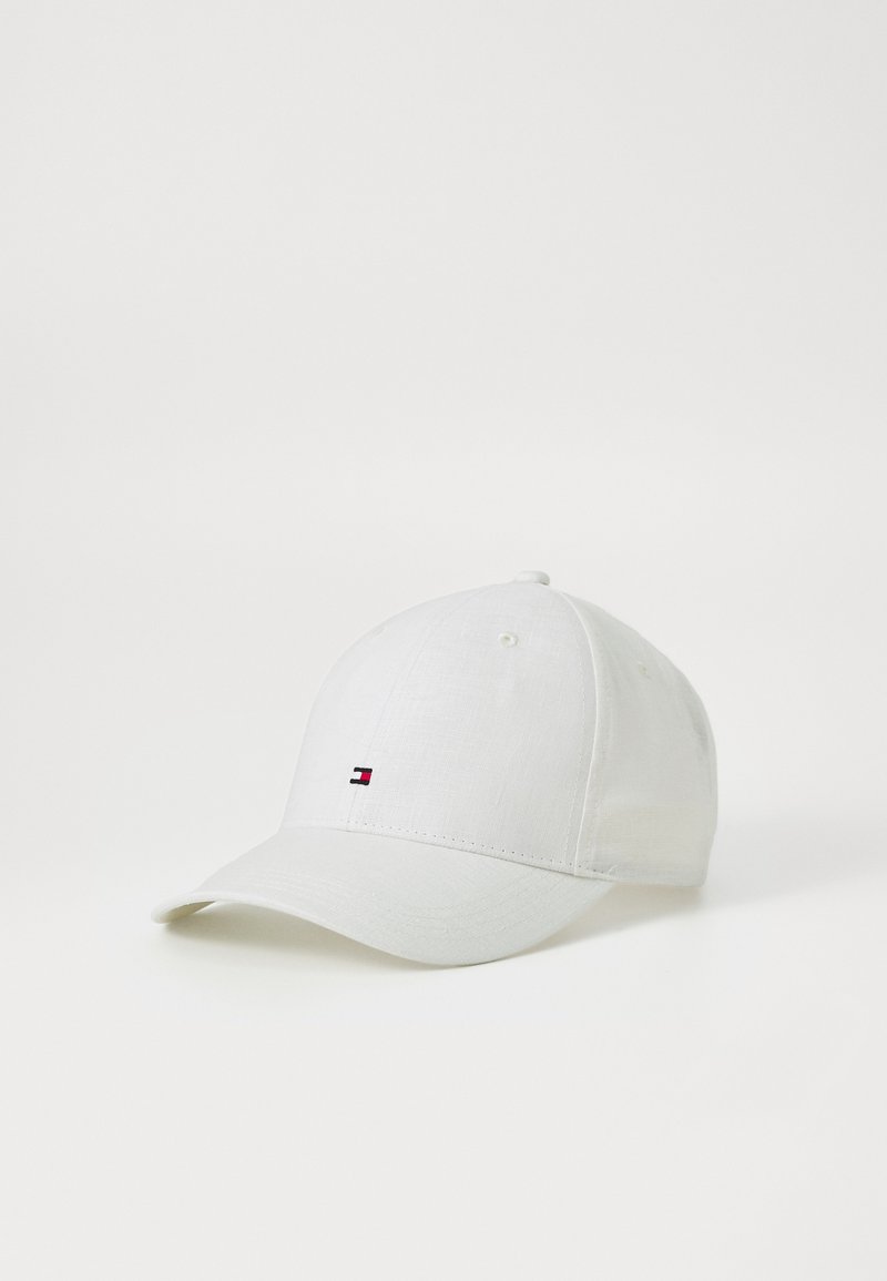 Cappello da baseball bianco realizzato in tessuto con una texture liscia. Presenta un piccolo logo ricamato con accenti rossi, bianchi e blu sul davanti.