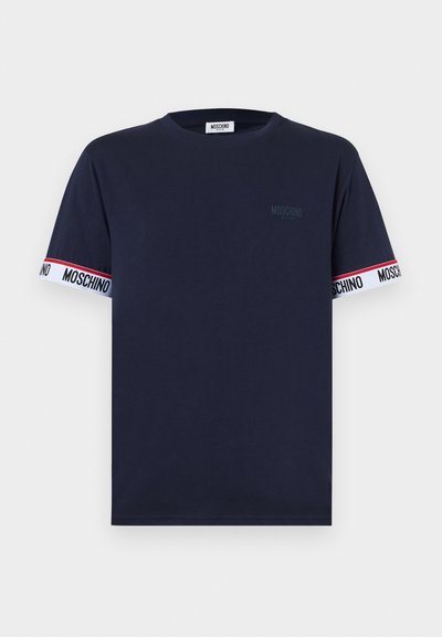 Σκούρο μπλε ναυτικό κοντομάνικο T-shirt με στρογγυλή λαιμόκοψη, διακοσμημένο με λευκές ταινίες με κόκκινες ρίγες και το κείμενο "MOSCHINO" στις μανσέτες των μανικιών.