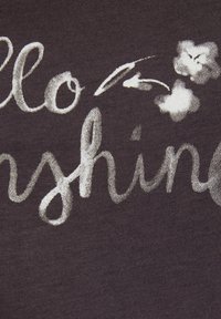 Donker stof met witte tekst "Hello Sunshine" en bloemaccenten. De textuur lijkt glad en licht rekbaar.